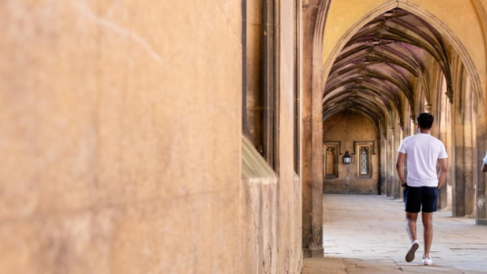 Students walking along a beautiful stone cloister in cambridge.
