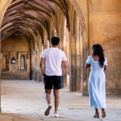 Students walking along a beautiful stone cloister in cambridge.