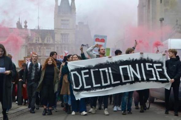 People walking along Kings Parade in Cambridge holding a 'decolonise' banner